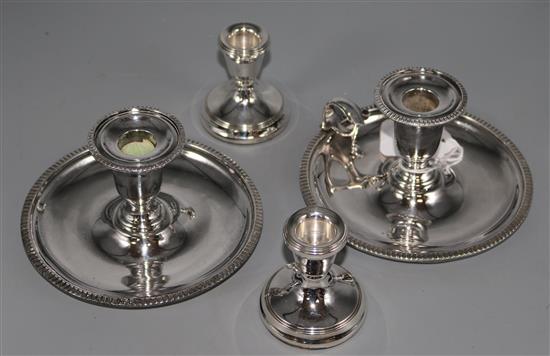 A modern pair of silver dwarf candlesticks and two silver plated chambersticks (one lacking handle).